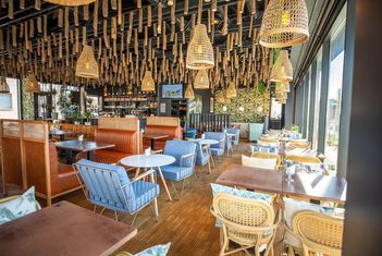 Stilvolles Restaurant-Interieur mit Korblampen, modernen Sitzgelegenheiten und Akzenten aus Holzdekor. slide-6