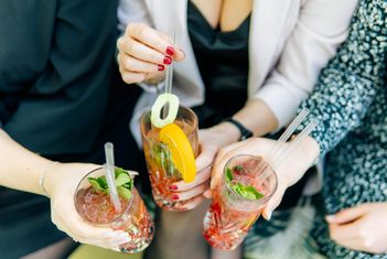 Vier Hände halten bunte Cocktails mit Garnituren. slide-14